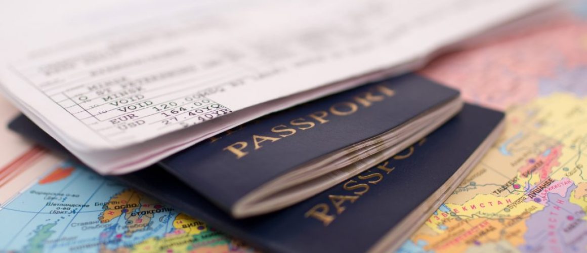 A boarding pass and two passports resting on top of a colourful world map.