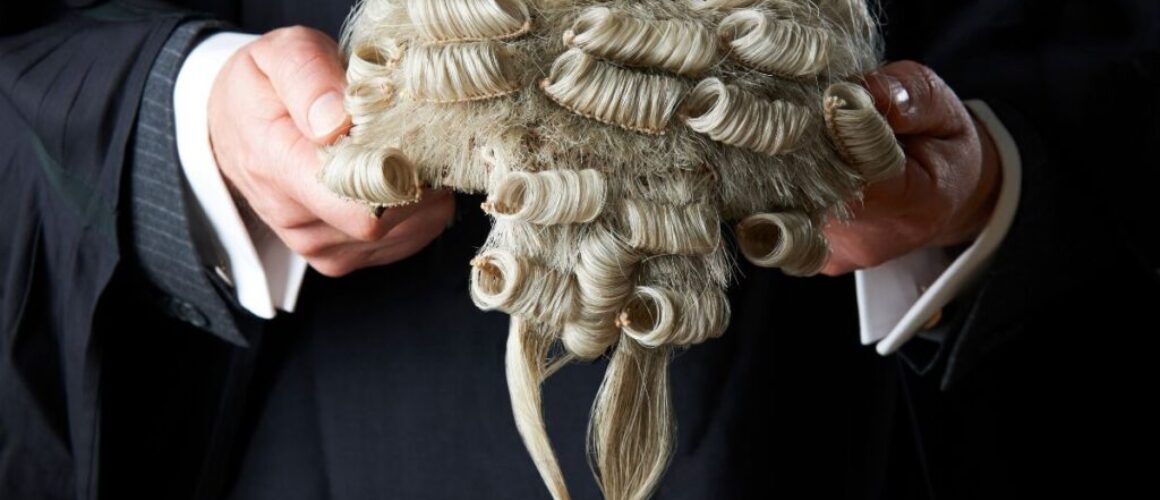 A barrister clutching his white wig in his hands to help illustrate Barristers First's blog answering the question, 'what is a direct access barrister?'.